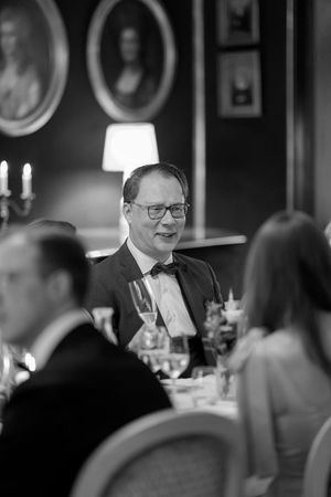 Black and white candid photos show a social gathering with people seated at tables in a dimly lit restaurant setting.
