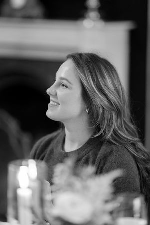 Black and white profile portrait of a person with long wavy hair looking upward in candlelit setting.