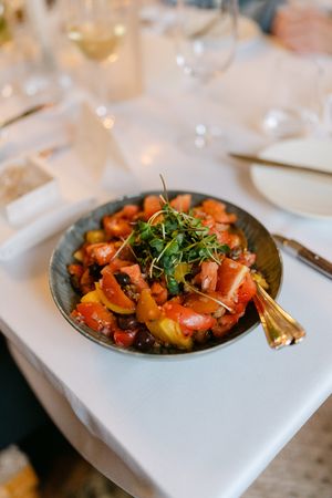 Colorful seafood dish garnished with fresh herbs served on white tablecloth in upscale restaurant setting.