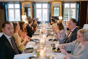 Guests seated at elegant dining tables during a formal event with candlelight and natural window lighting.