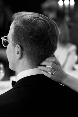 Black and white image showing the backs of several people's heads at a formal event.