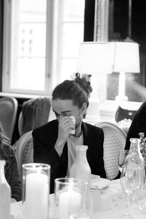 Black and white photo of people sitting at a dining table with glasses and place settings in a restaurant setting.