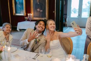 A group of wedding guests share a joyful moment together at a candlelit reception table.