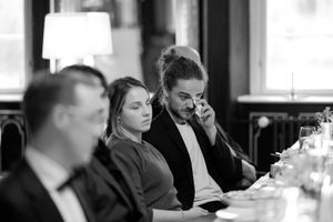 Wedding guests in formal attire share laughter and conversation during a reception dinner at an elegant venue.