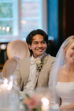 A joyful moment captured during a wedding reception as guests smile and celebrate at a formal dining table.