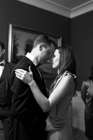 A romantic black and white photograph of a couple sharing an intimate moment while dancing at an indoor event.