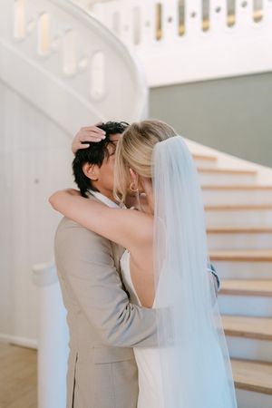 A romantic first kiss sequence between newlyweds at their wedding ceremony with a flowing white veil.