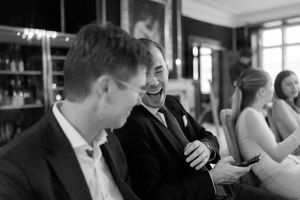 People enjoying conversation and laughter during a social gathering in a dimly lit indoor setting.