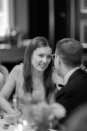 A couple shares an intimate moment while dining at a restaurant, shown in a black and white candid photo.