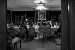 Black and white photograph of an elegant dining room interior with chandeliers and formal table settings.