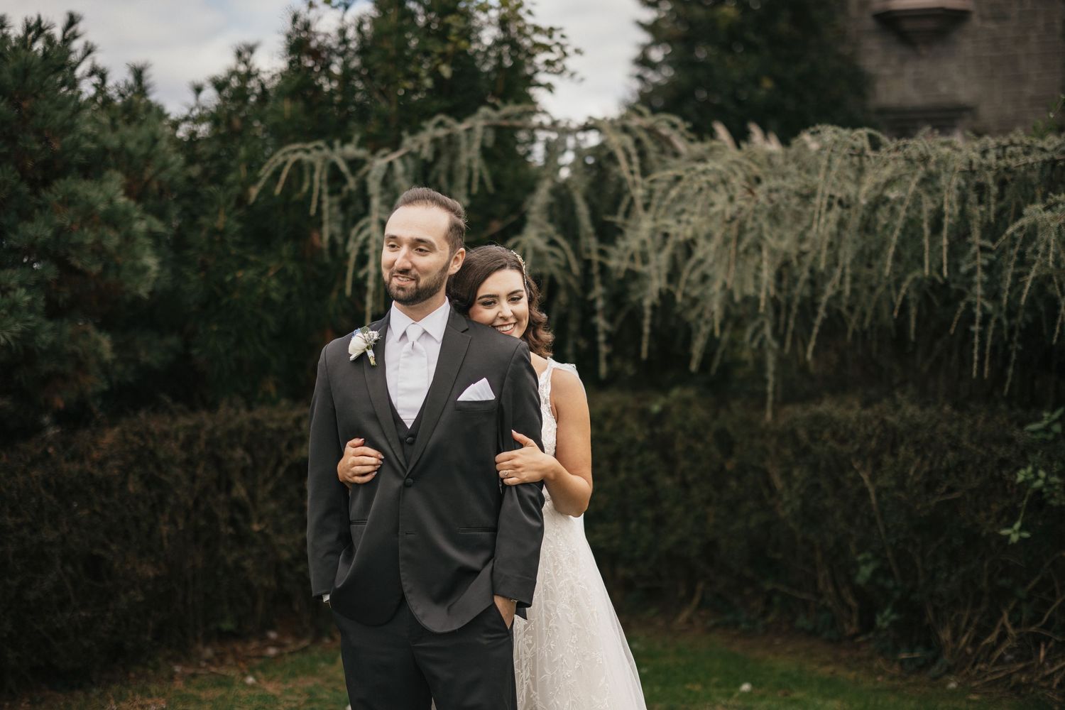 Wedding ceremony setup with white chairs on a lush green lawn facing a historic stone church under cloudy skies.