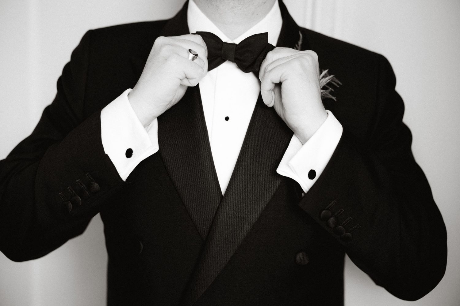 Four people wearing formal black tuxedos and bow ties pose together in a black and white photograph.