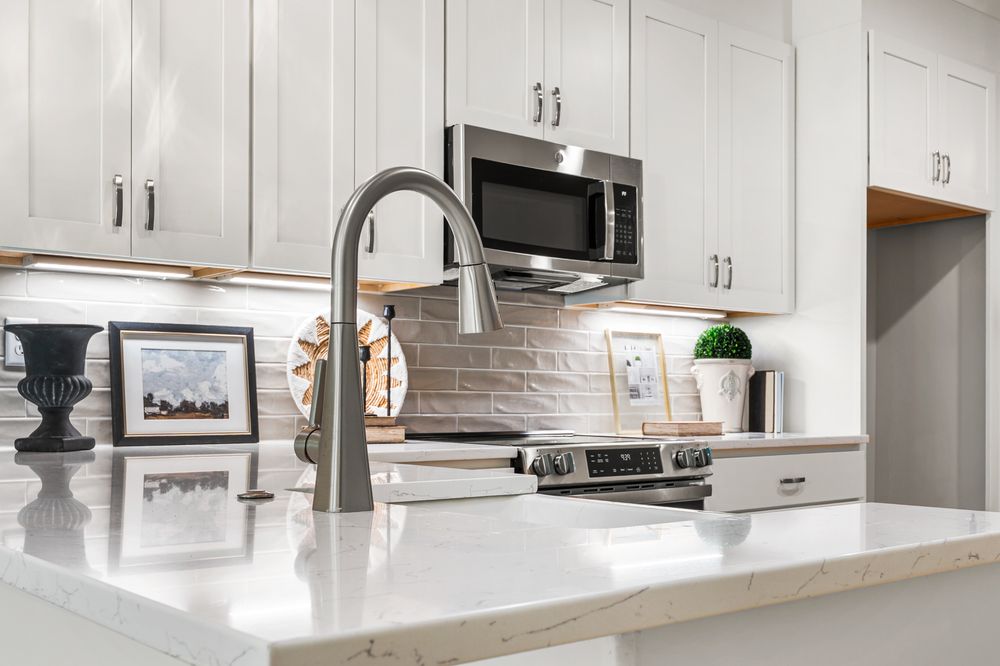 Elegant kitchen with white cabinets, quartz countertops, subway tile backsplash, and stainless steel appliances.