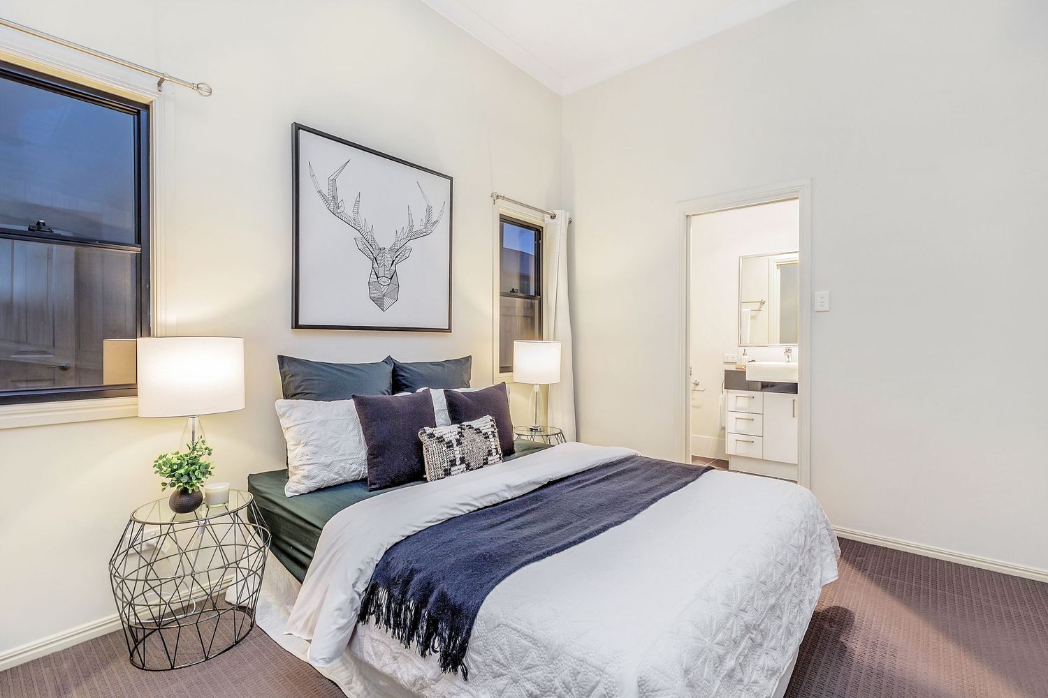 Elegant bedroom with high ceilings, deer artwork, and ensuite access.