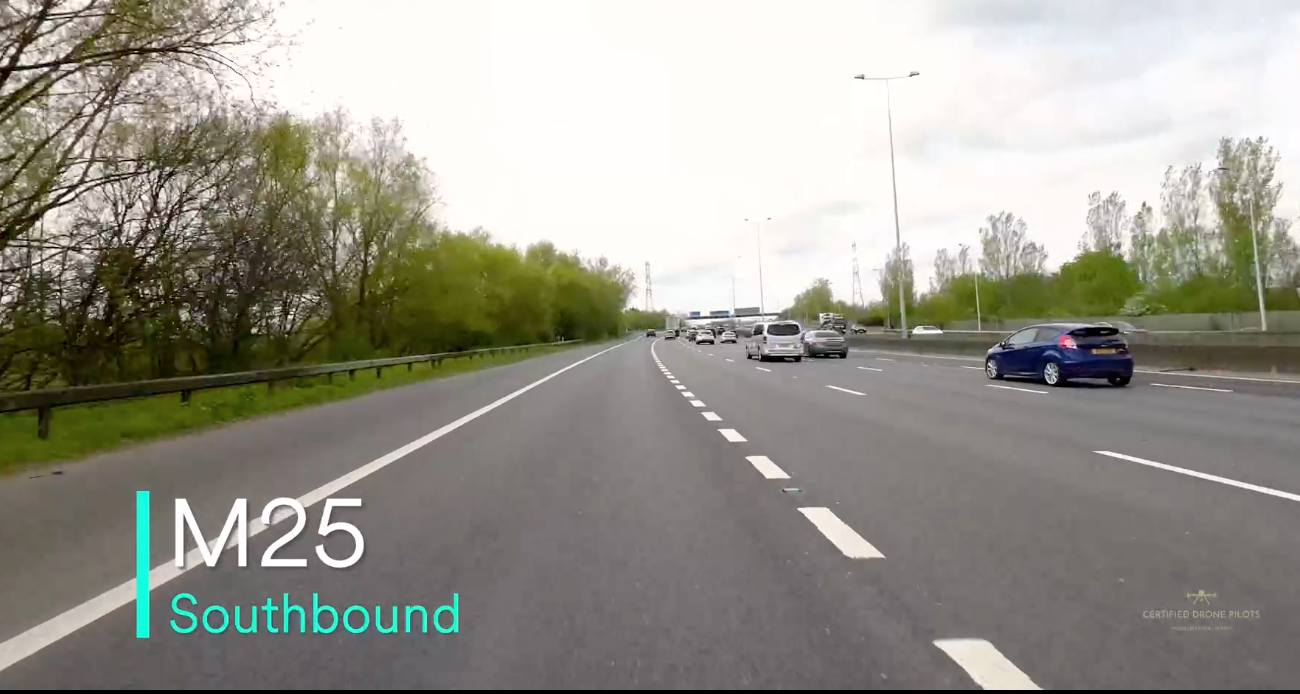 Dashcam view of M25 motorway southbound with light traffic on a clear day, surrounded by green trees.