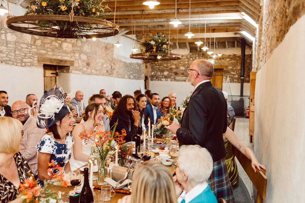 Wedding guests mingle and socialize during a reception in an elegant rustic venue with exposed brick walls and warm lighting.