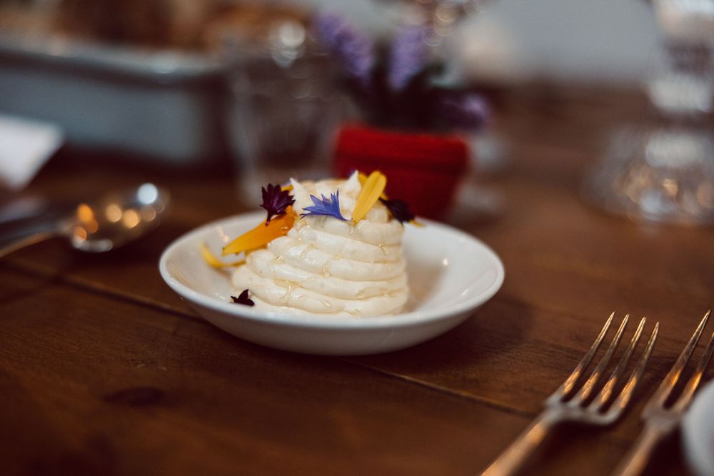 A plated dessert with whipped cream and garnishes served on a rustic wooden table with a fork beside it.