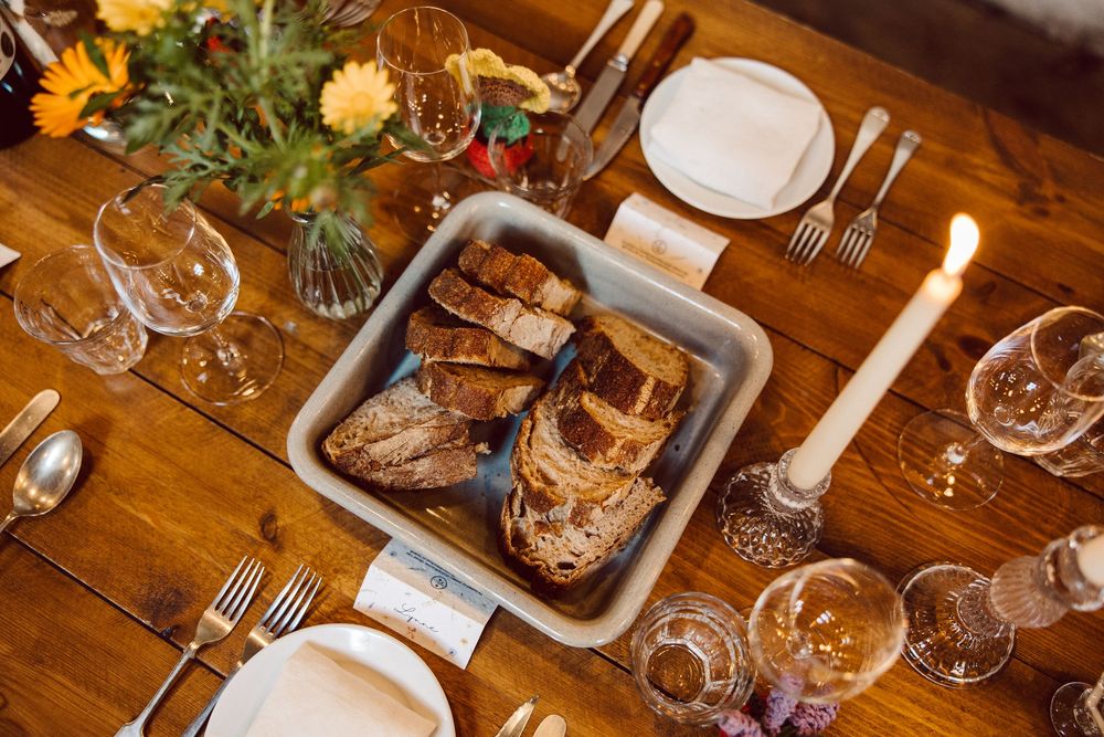 Elegant dinner table setting with lit candles, wine glasses, and rustic wooden decor for a cozy gathering.
