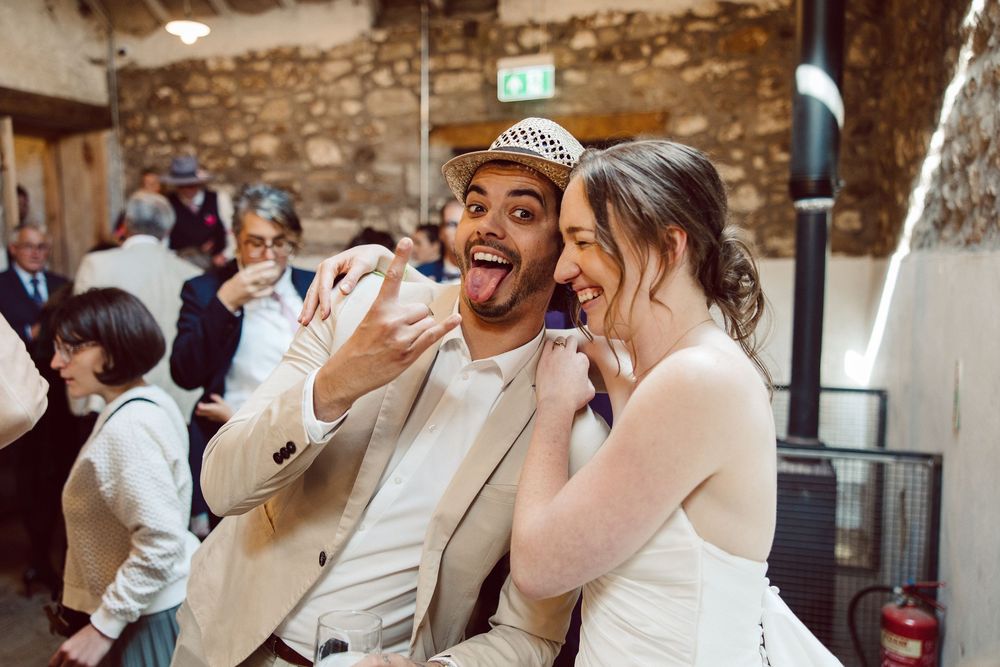 Wedding guests dance and celebrate together on a rustic brick-walled dance floor at a reception.
