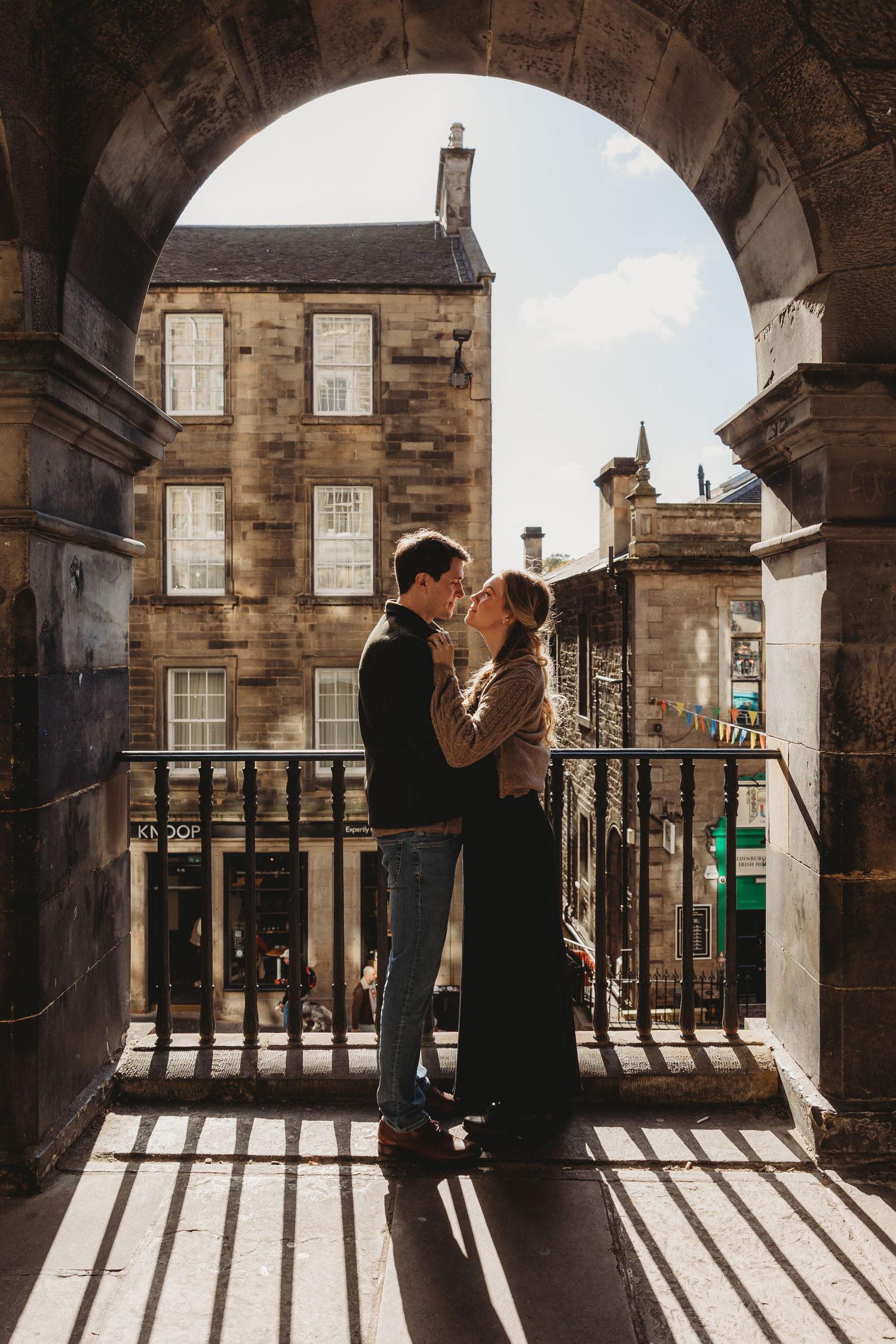 A couple strolls down a historic cobblestone street lined with traditional European architecture.
