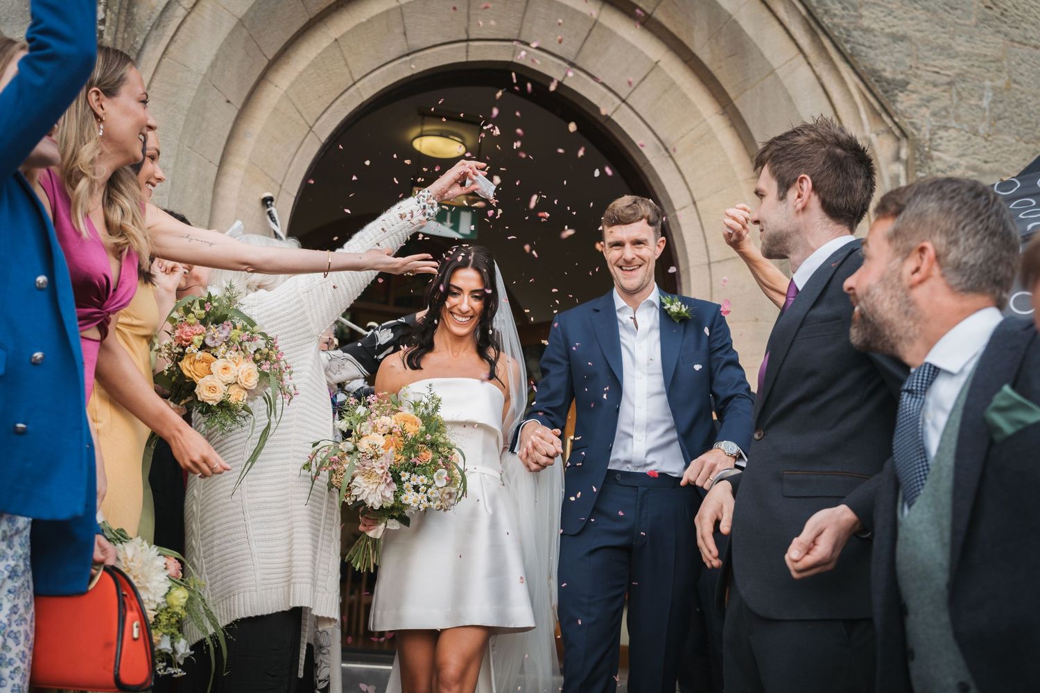A series of wedding photos showing candid moments between couples and guests at a rustic stone venue.
