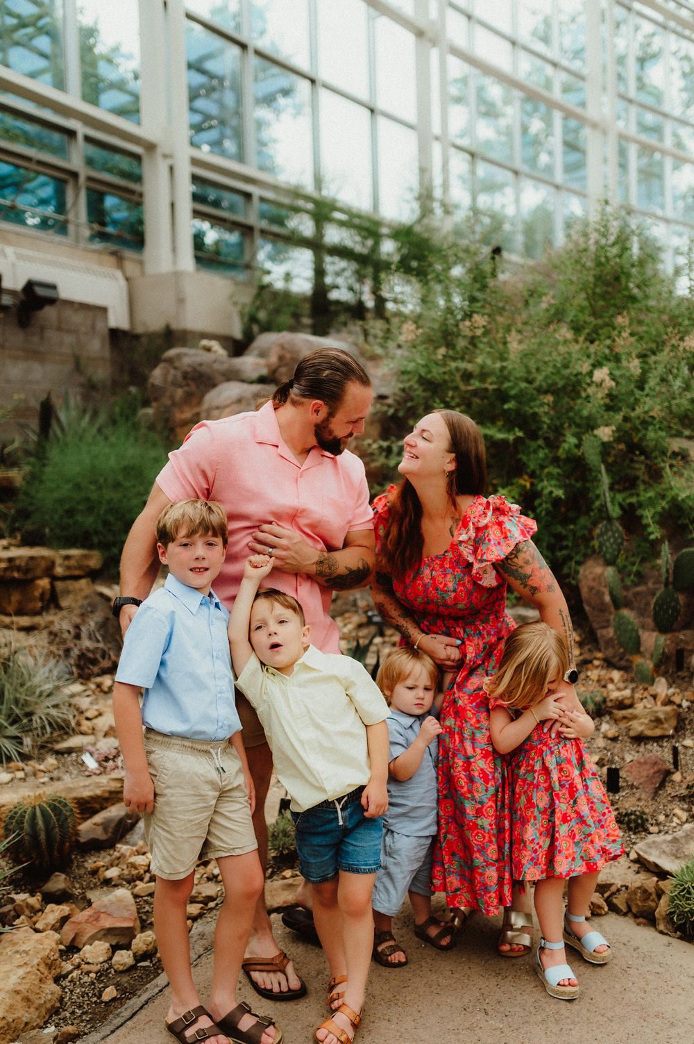 Family of five enjoying a playful moment together while sitting on stone steps in an outdoor garden setting.