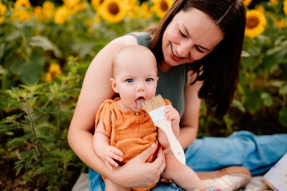 Joyful moment shared between parent and baby in a vibrant sunflower field on a summer day.