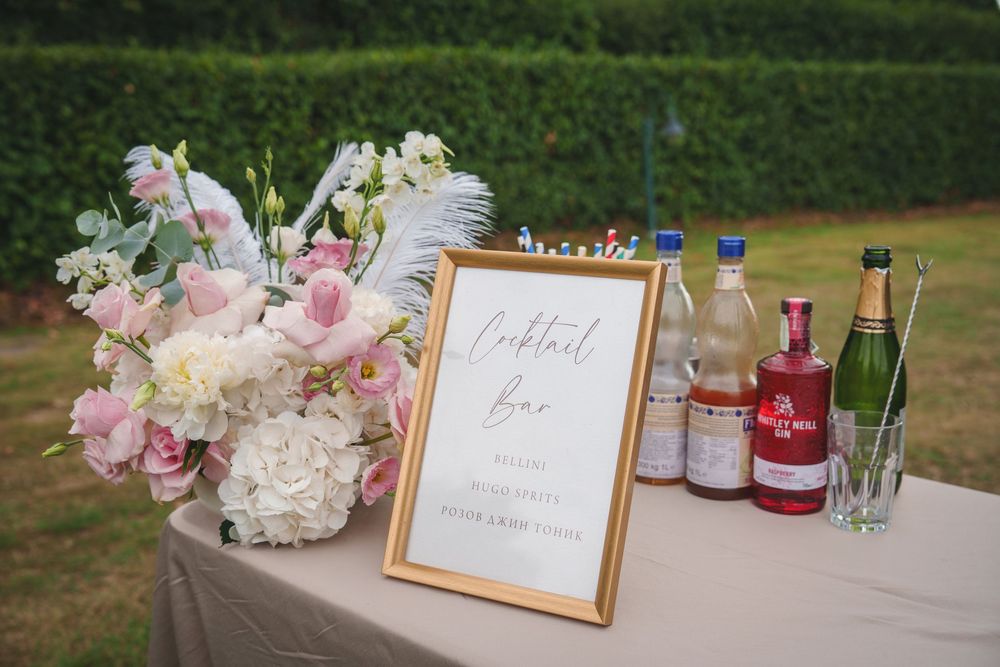 Elegant outdoor wedding reception table decorated with pink and white floral arrangements and wine bottles.