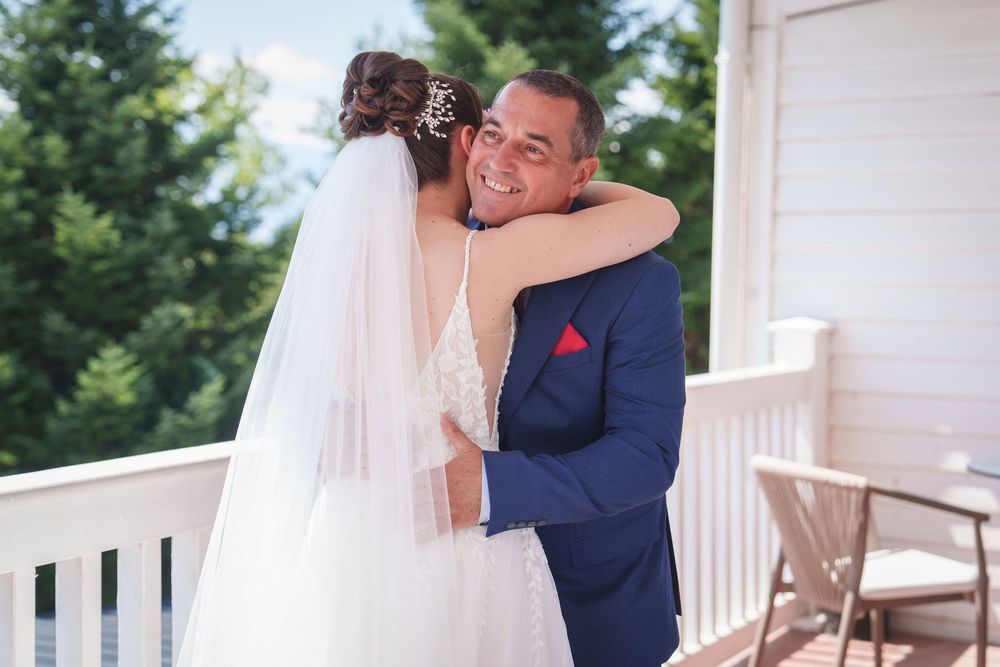 A couple shares an intimate moment on a white porch during their wedding ceremony.