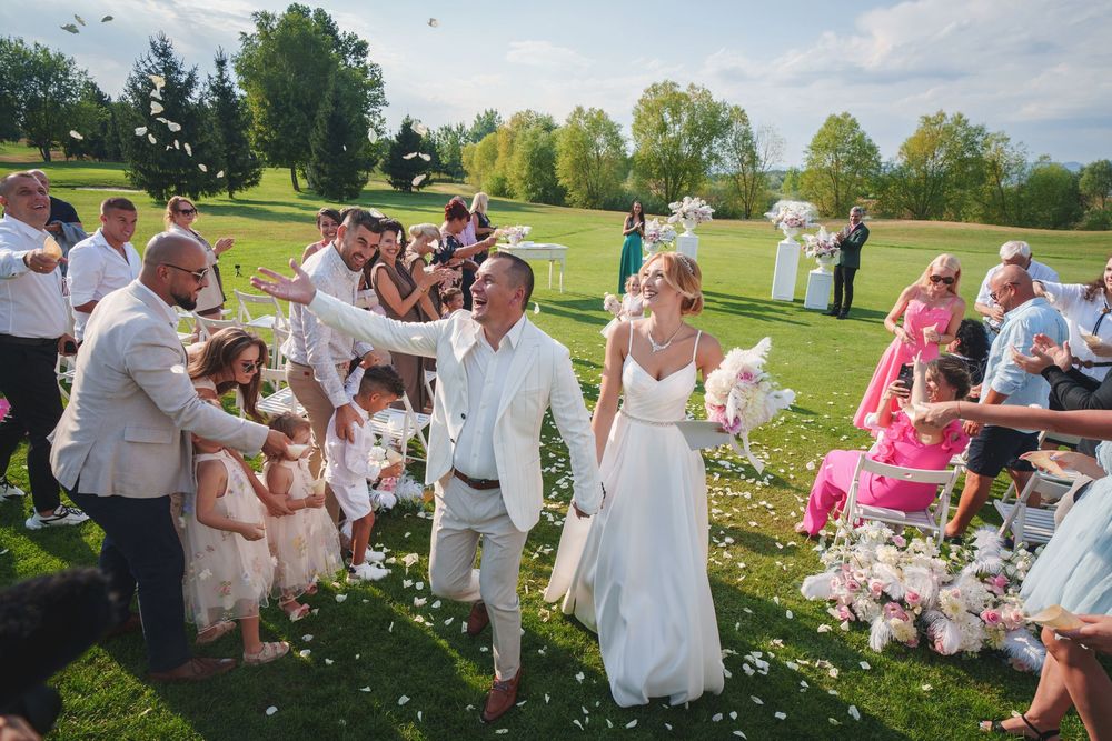 Wedding guests gather on a lush green lawn during an outdoor summer celebration.