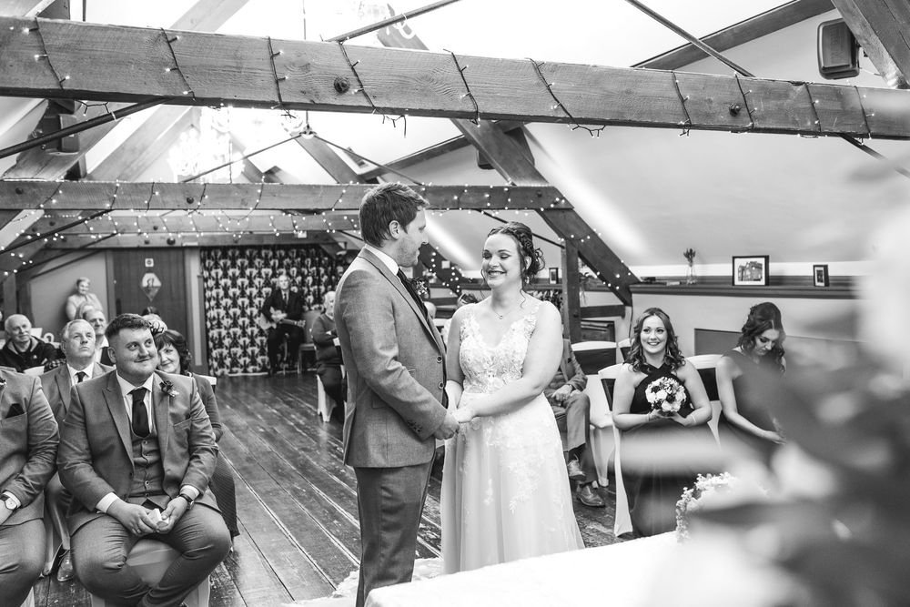 Black and white panoramic view of guests mingling at an outdoor wedding celebration.