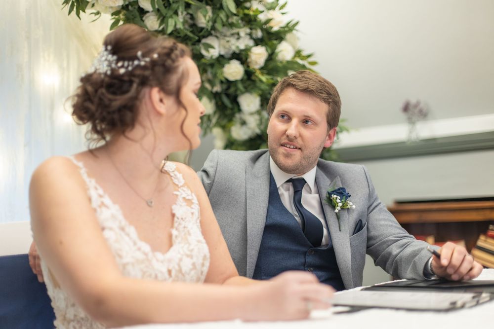 Wedding reception scene with table settings and floral decorations in an elegant indoor venue.