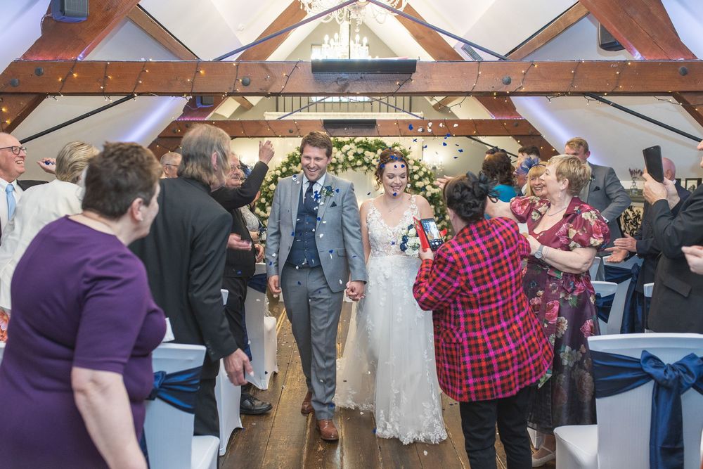 Wedding guests socializing in a rustic wooden beam venue with natural lighting.