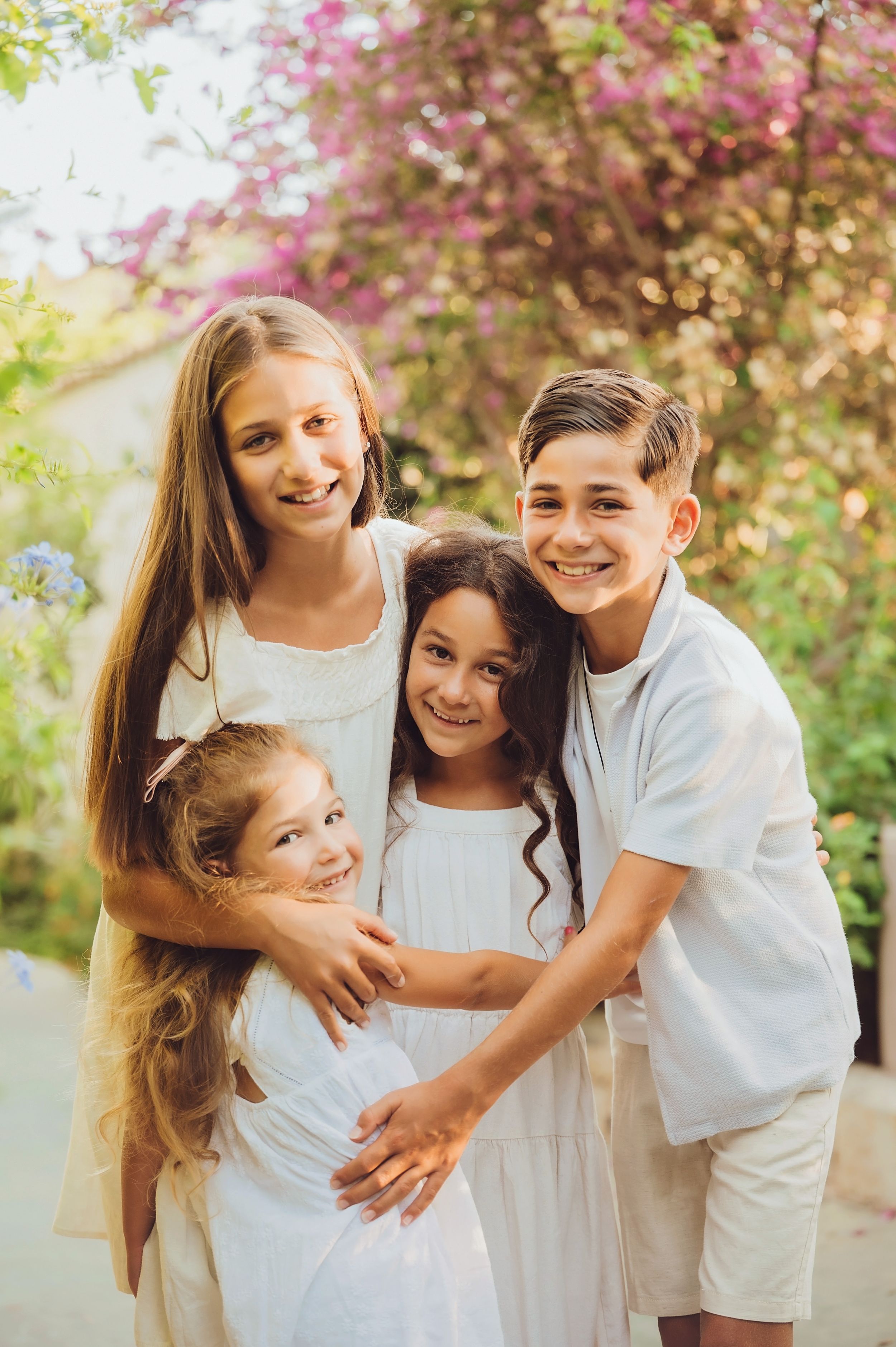 A close group portrait in white outfits against blooming spring trees.