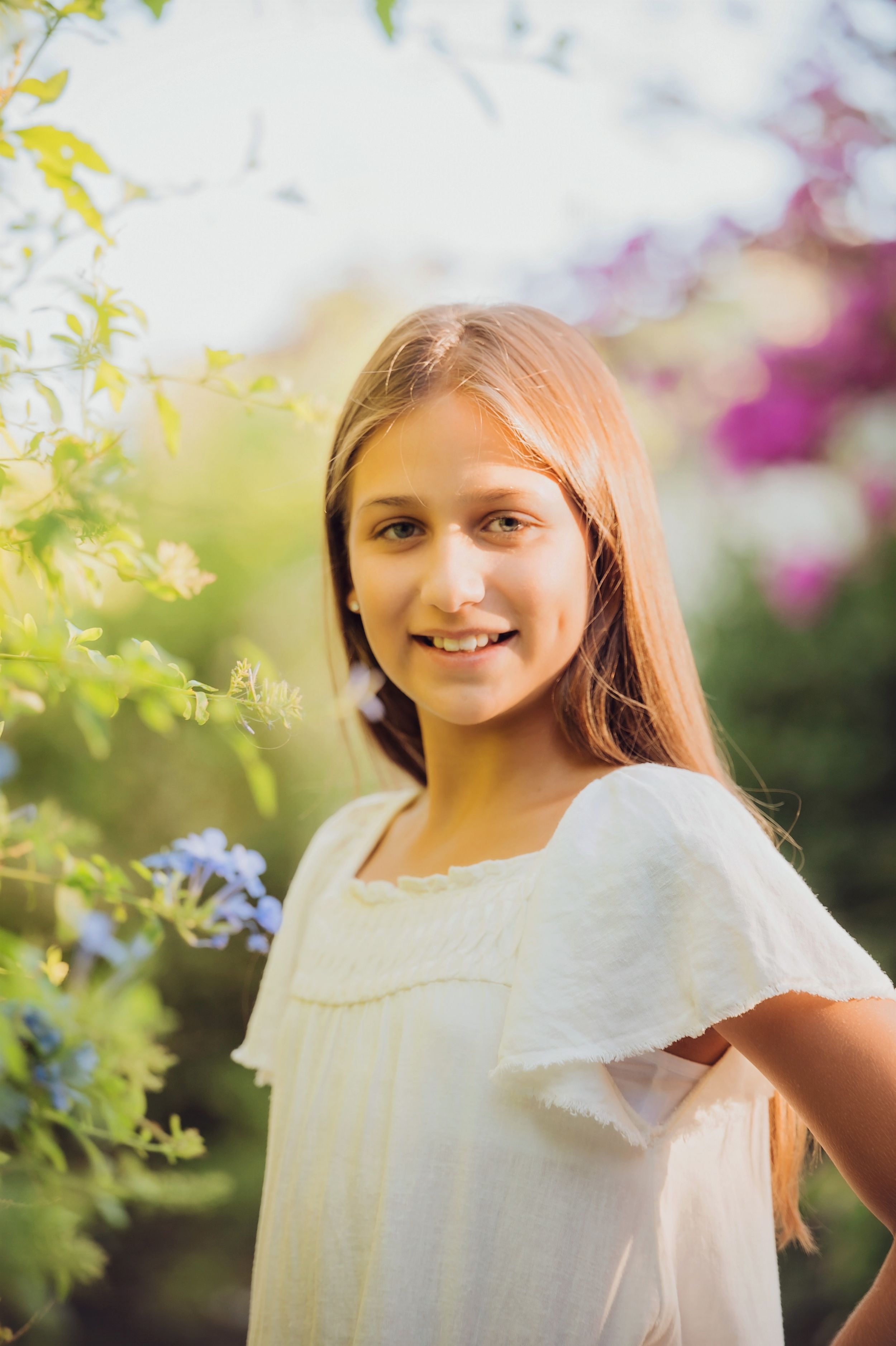 A candid portrait in a garden with blooming flowers and soft natural lighting.