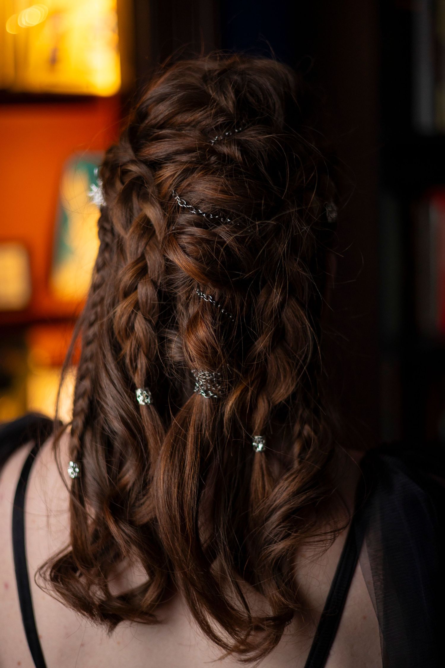 Close-up view of an intricate Viking-inspired braided hairstyle with delicate silver flower accessories woven into dark brown hair.