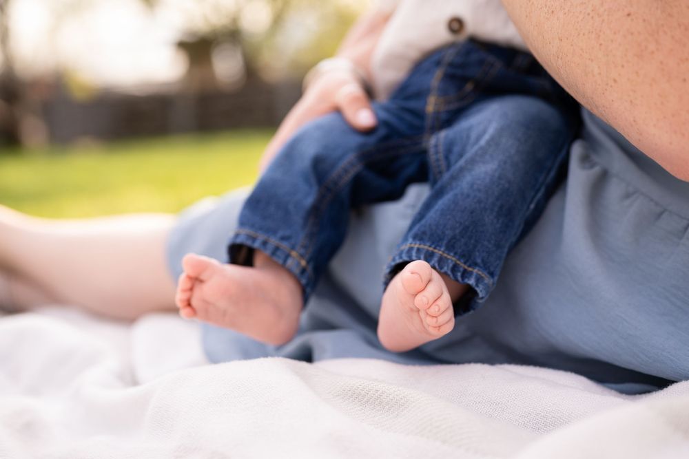 A baby wearing navy blue clothing lies on a white blanket while being photographed from different angles.