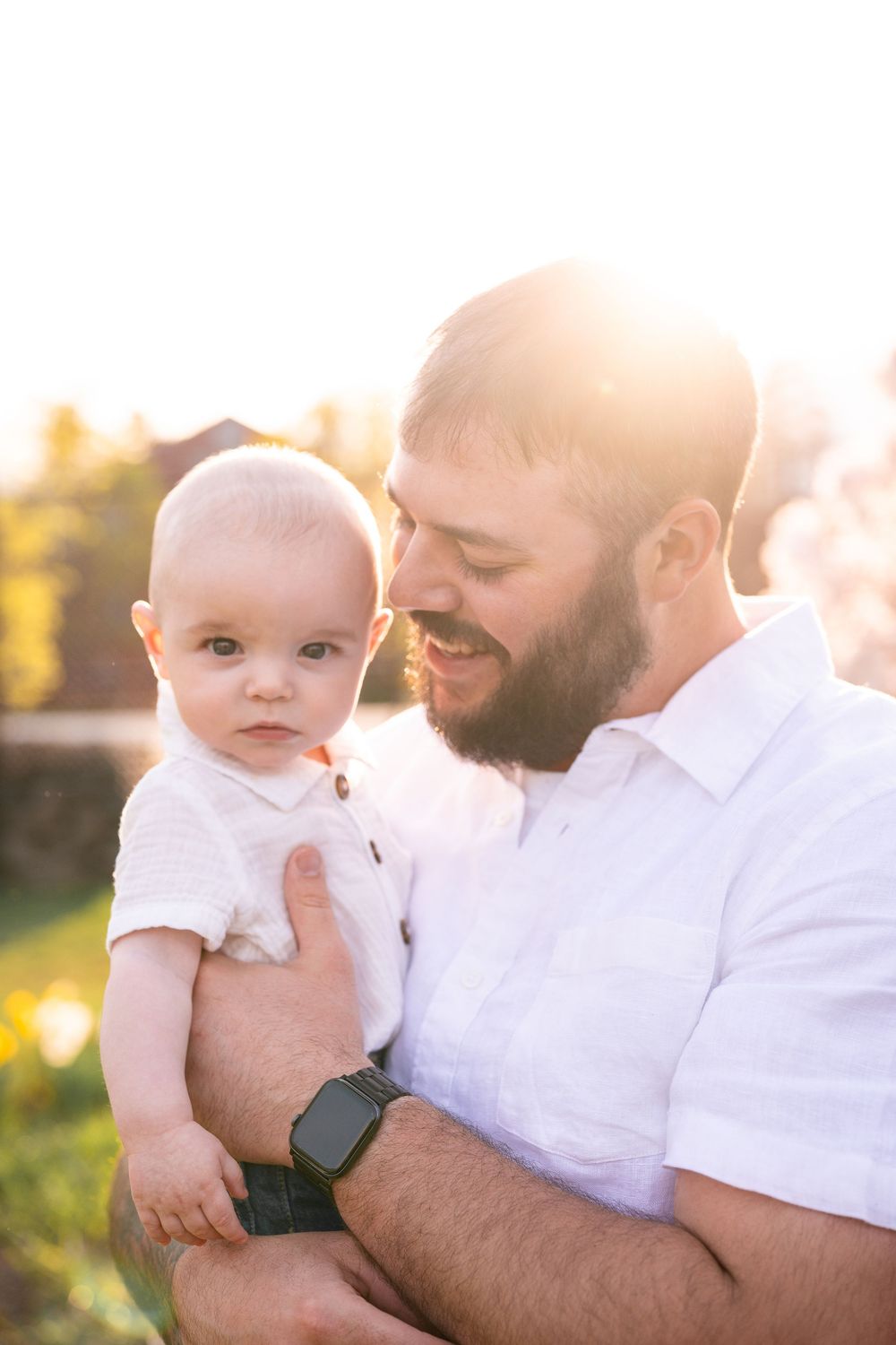 A tender moment between parent and baby captured in warm sunlight during an outdoor photo session.