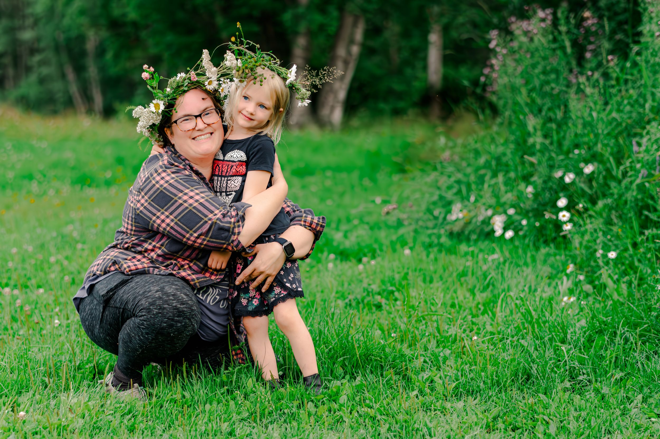 A couple sits together on lush grass while sharing intimate moments in a green outdoor setting.