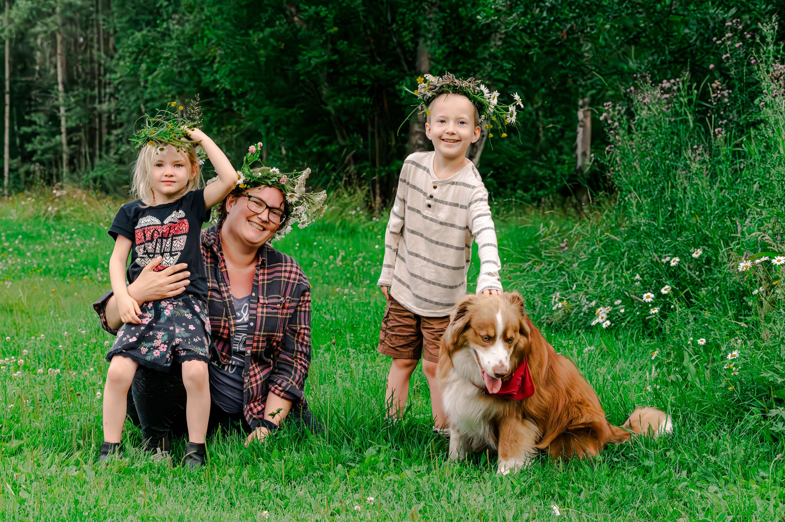 Children and a golden retriever dog playing together in a lush green summer meadow with wildflowers.