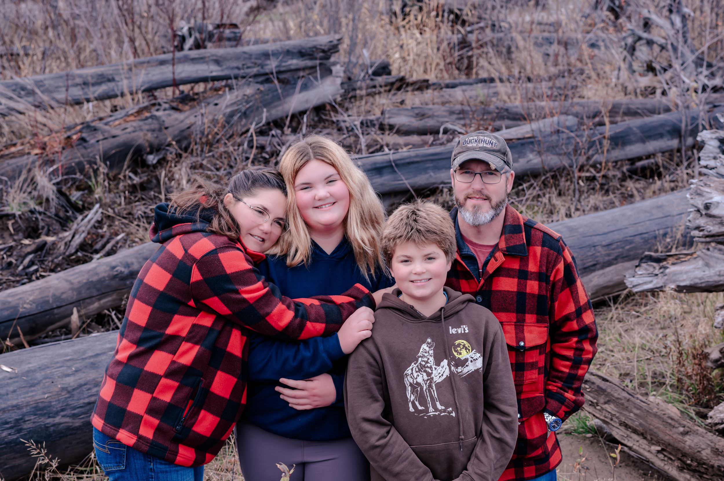A series of outdoor family photos taken in a rustic setting with people wearing red and black buffalo plaid shirts.