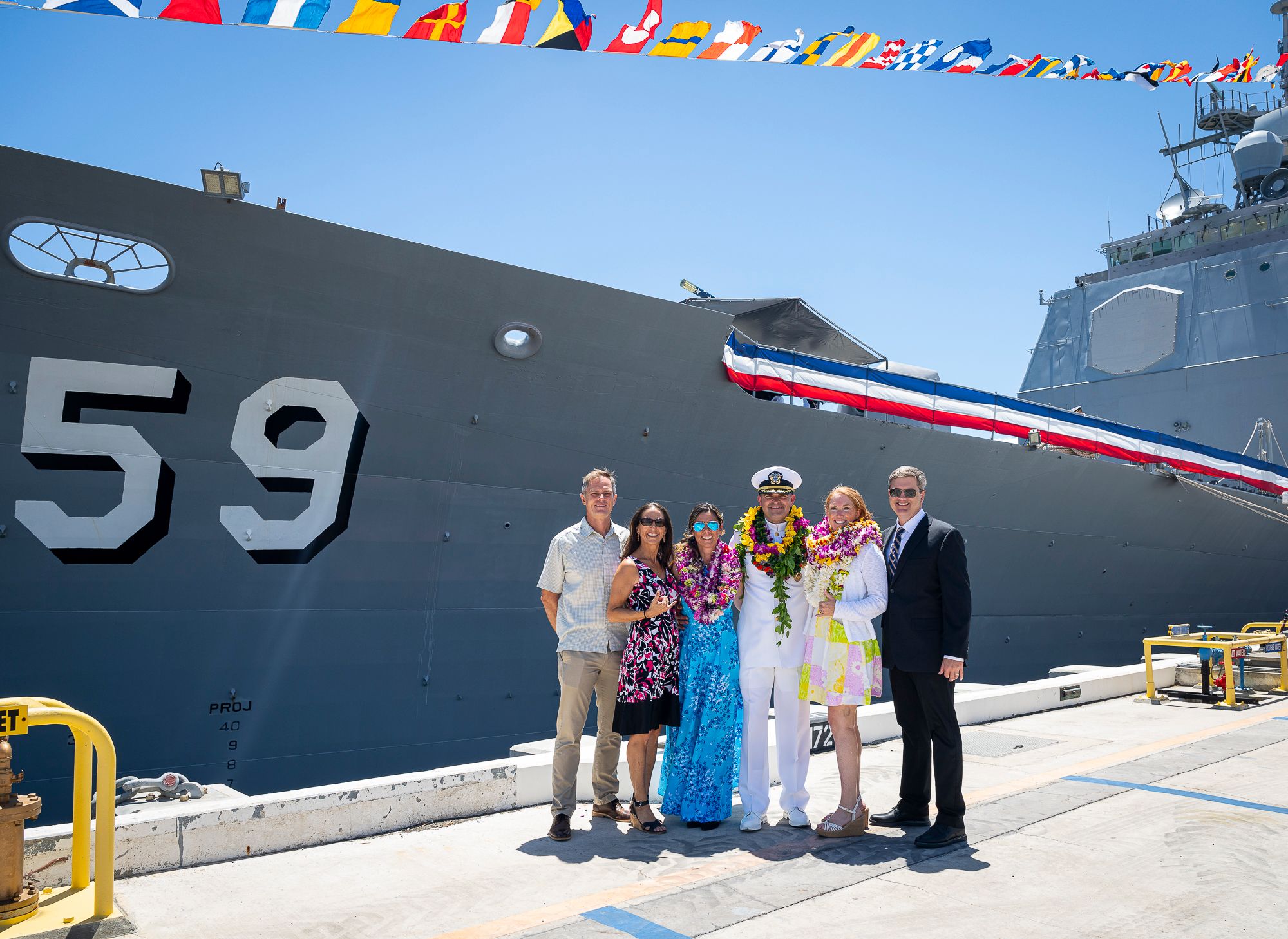Pearl Harbor military family photos on U.S. Navy ship deck with colorful flags and military vessel number 59 visible.