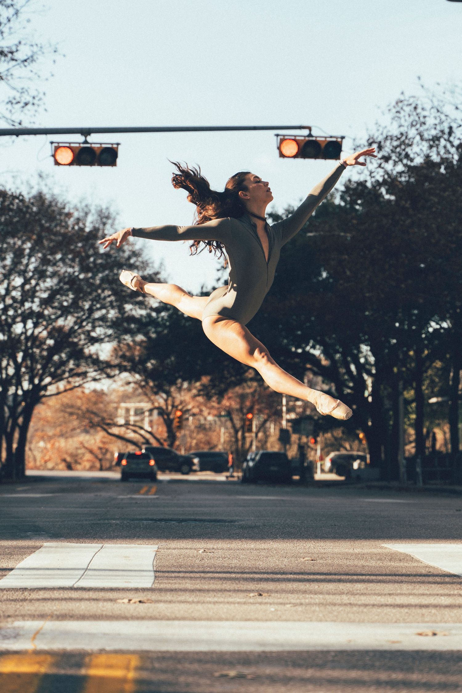 Ballerina leaping through the air on a downtown Austin crosswalk during a sunrise dance photography session