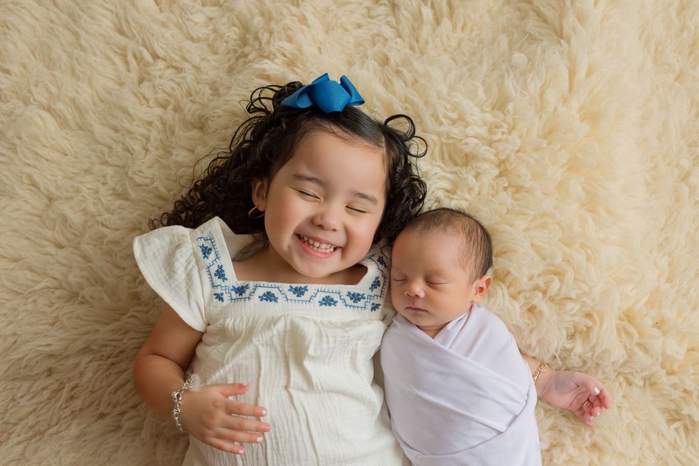 Older sister cuddling her newborn sibling during a studio newborn session