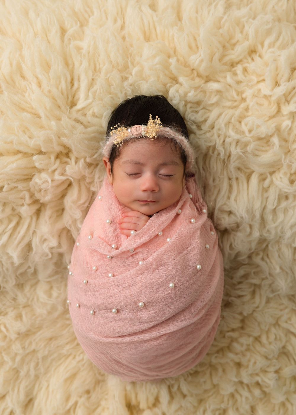 Newborn baby girl wrapped in pink during a studio newborn session