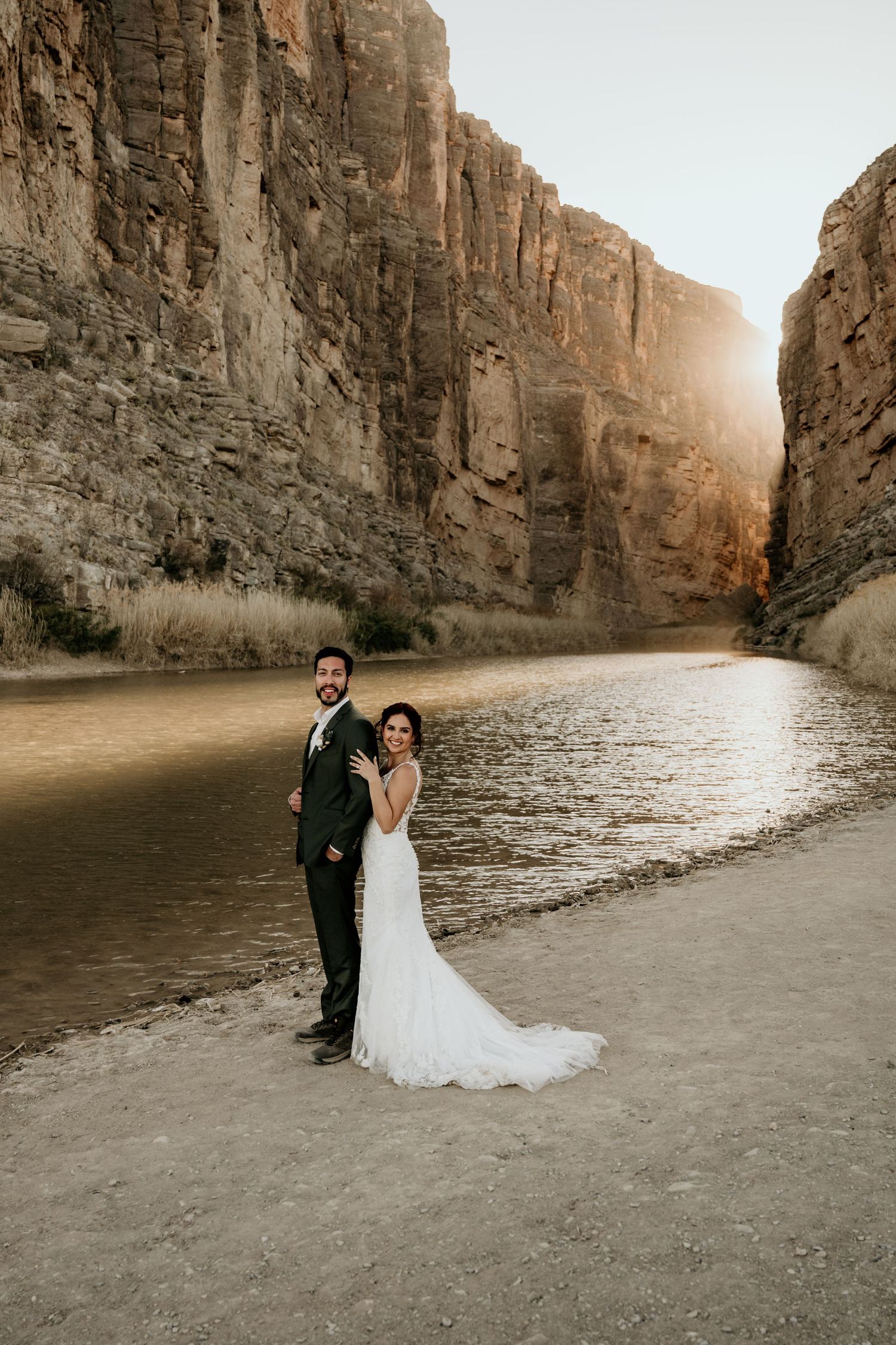 Wedding photography session in a scenic canyon with water and towering rock walls.