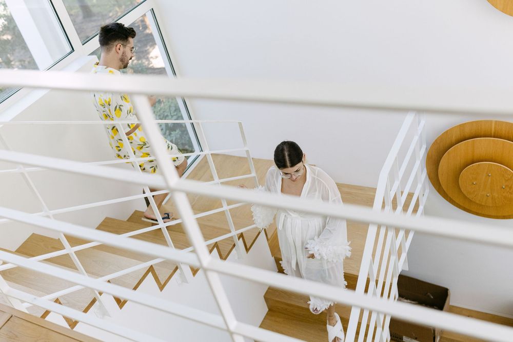 Bride and groom crossing paths on staircase during morning preparations in Cascais.