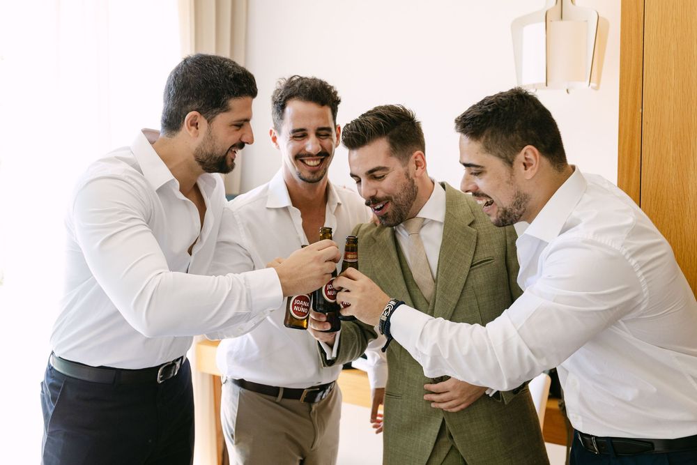 Groom celebrating with friends during relaxed wedding morning preparations in Lisbon, Portugal.