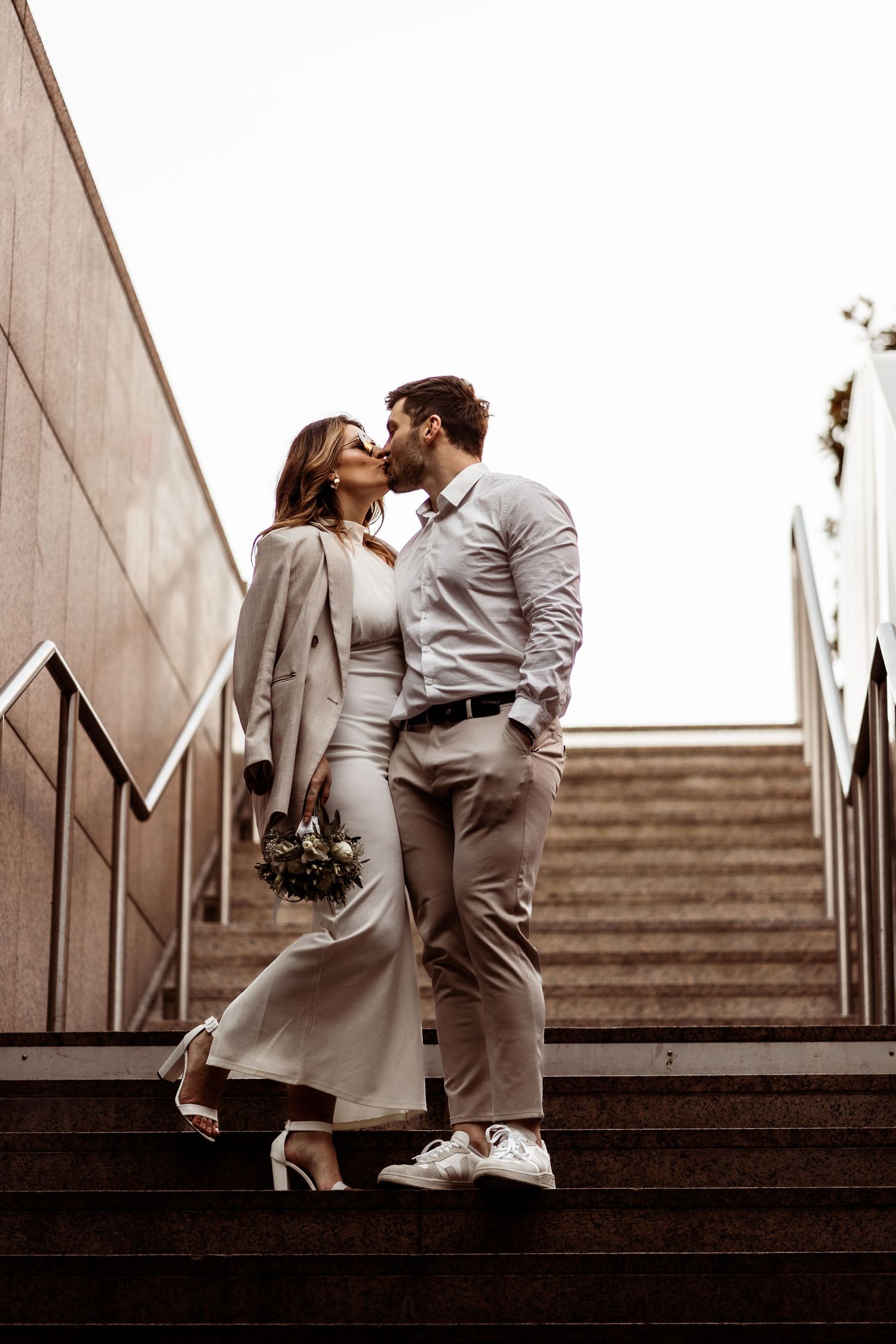 A romantic moment between a couple in formal attire on concrete stairs.