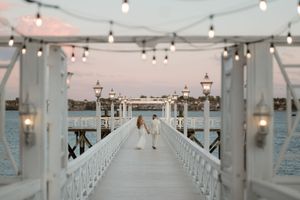 White wooden church pews line both sides of an aisle leading to an altar under hanging string lights.